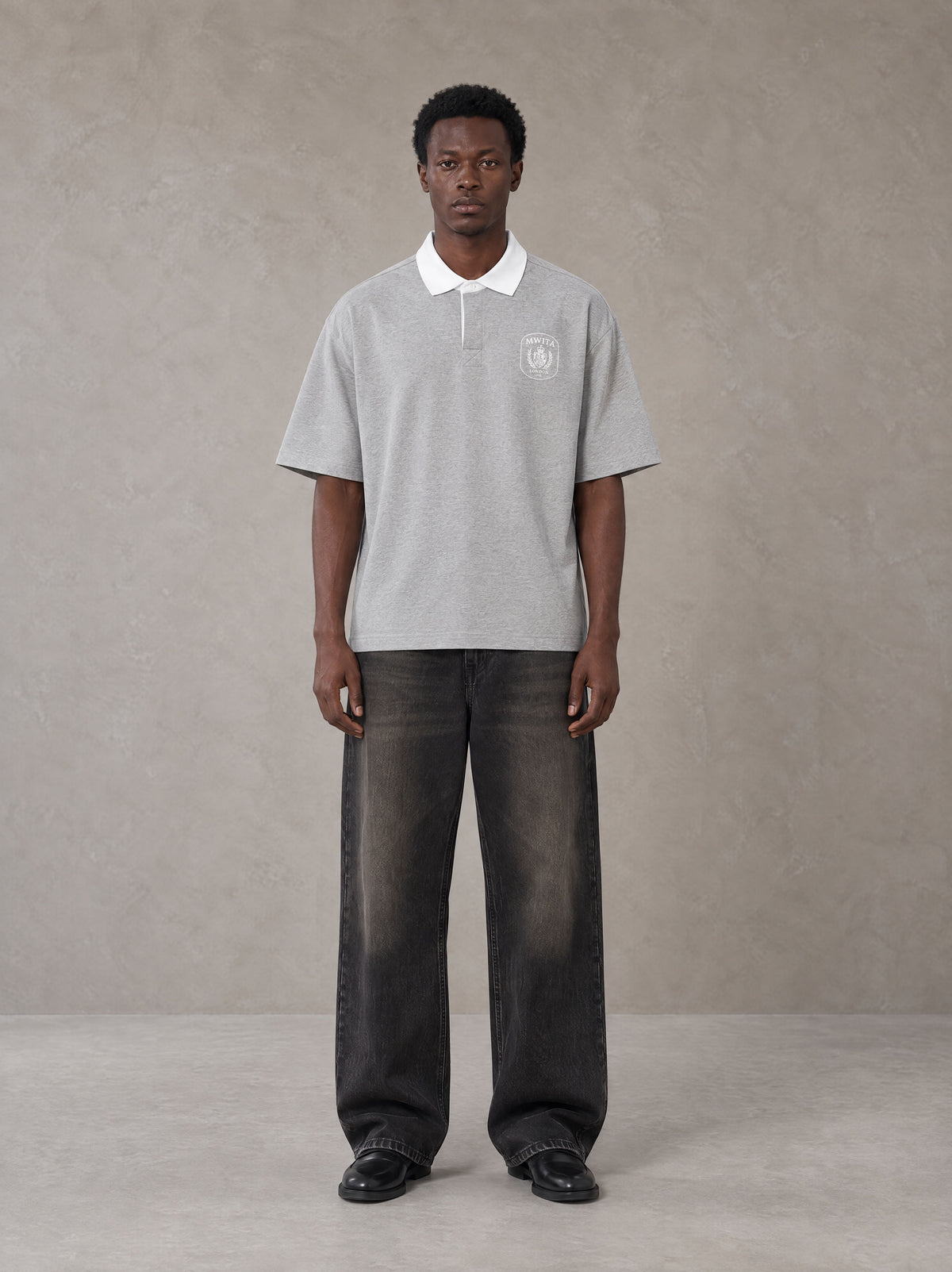Model wearing the SM Royal Emblem Polo T-shirt in Floral Grey, front view.