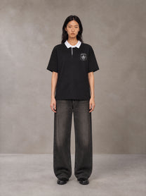 Model wearing the SM Royal Emblem Polo T-shirt in Midnight Black, front view.