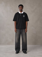 Model wearing the SM Royal Emblem Polo T-shirt in Midnight Black, front view.