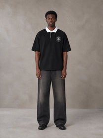 Model wearing the SM Royal Emblem Polo T-shirt in Midnight Black, front view.