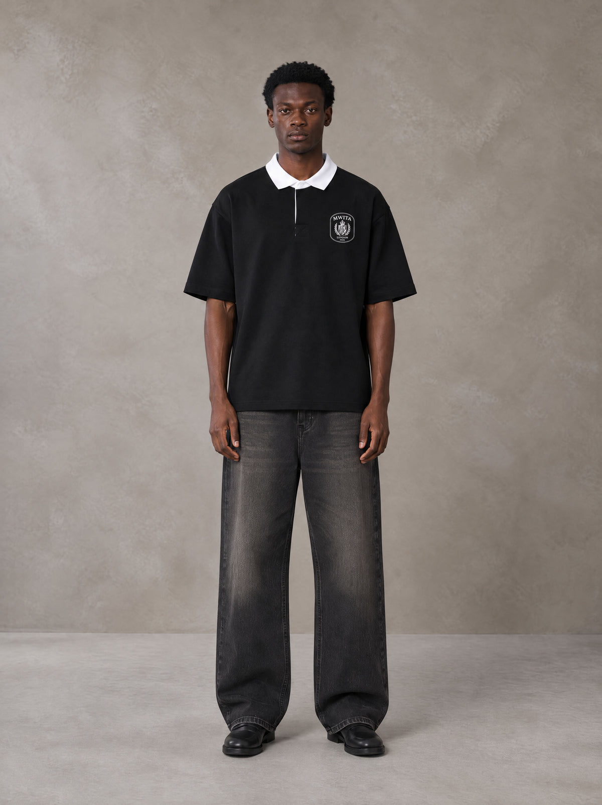 Model wearing the SM Royal Emblem Polo T-shirt in Midnight Black, front view.