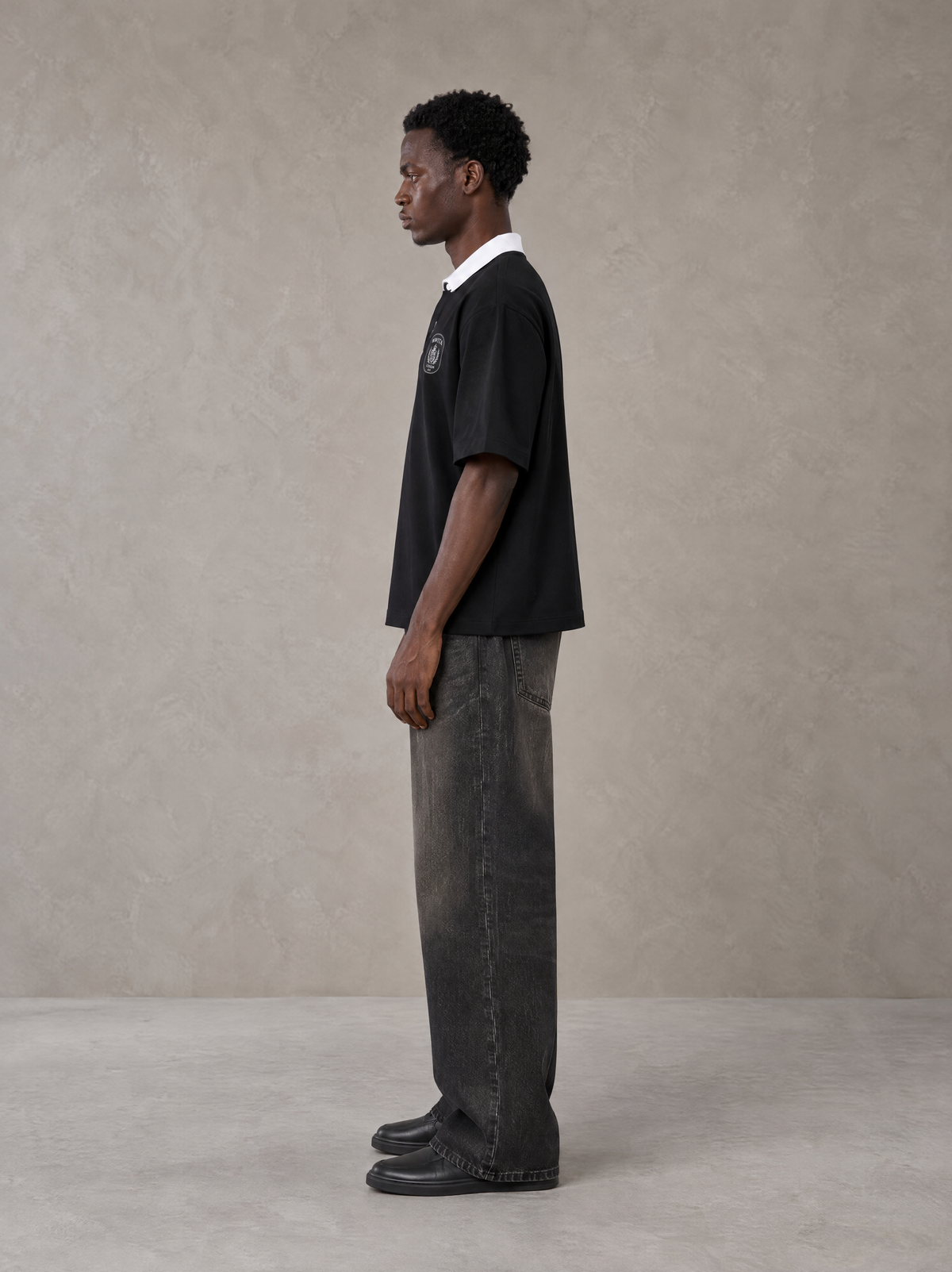 Model wearing the SM Royal Emblem Polo T-shirt in Midnight Black, side profile.