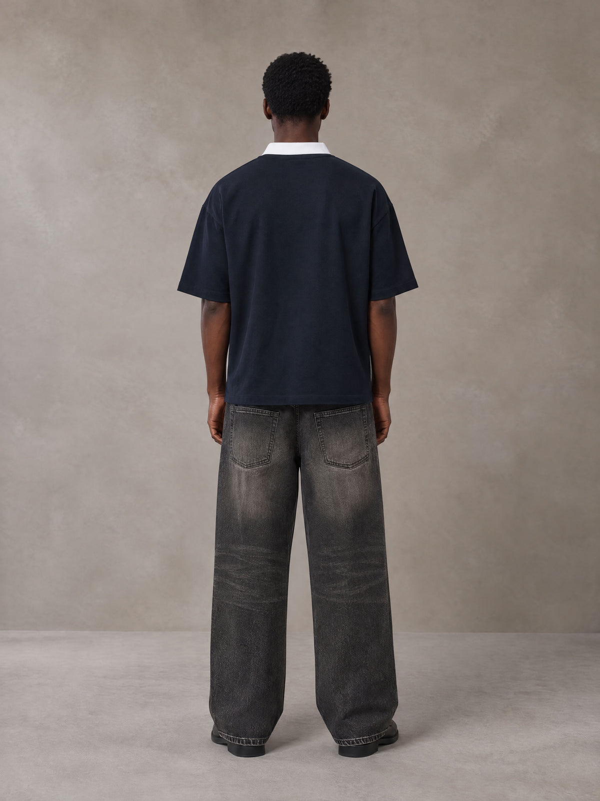 Model wearing the SM Royal Emblem Polo T-shirt in Oxford Navy, rear view.