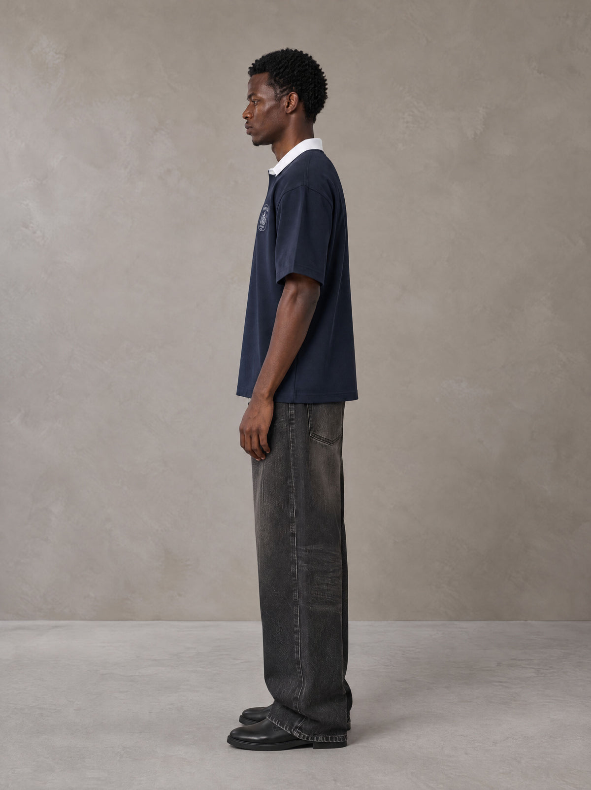 Model wearing the SM Royal Emblem Polo T-shirt in Oxford Navy, side profile.