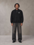 Model wearing the SM Royal Emblem Sweatshirt in Midnight Black, front view.