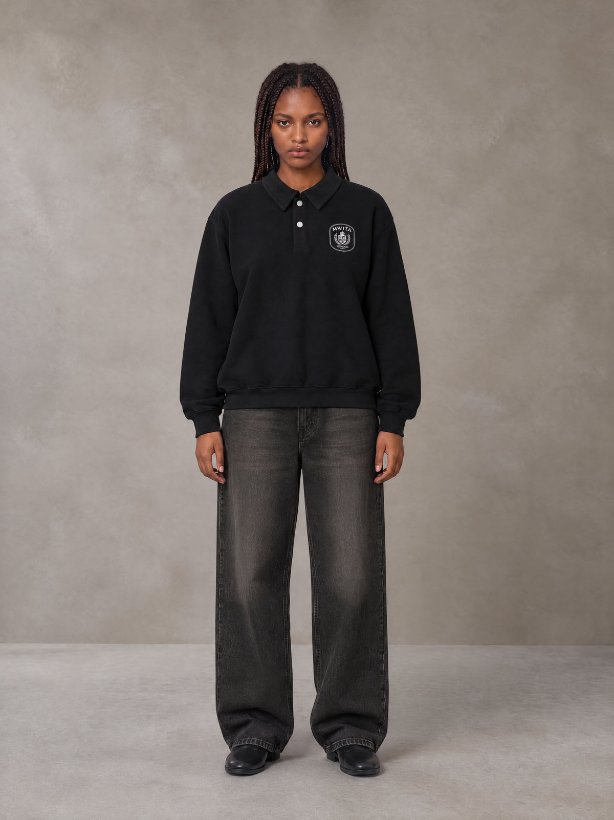 Model wearing the SM Royal Emblem Sweatshirt in Midnight Black, front view.