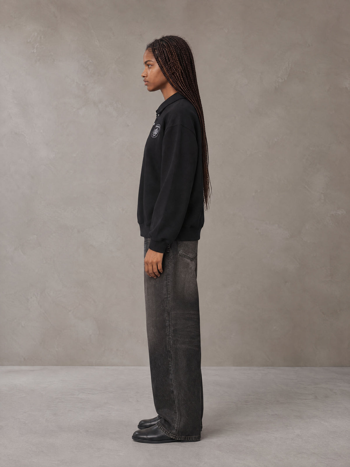 Model wearing the SM Royal Emblem Sweatshirt in Midnight Black, side profile.