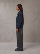 Model wearing the SM Royal Emblem Sweatshirt in Oxford Navy, side profile.