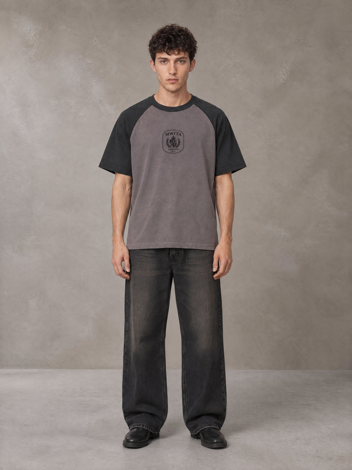 Model wearing the SM Royal Emblem T-shirt in Coffee Grey, front view.