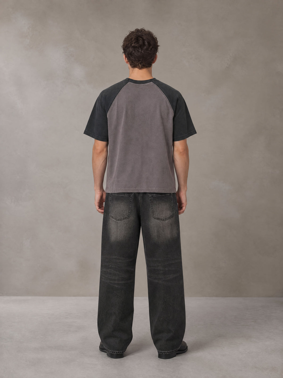 Model wearing the SM Royal Emblem T-shirt in Coffee Grey, rear view.