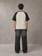 Model wearing the SM Royal Emblem T-shirt in Oatmeal Cookie, rear view.