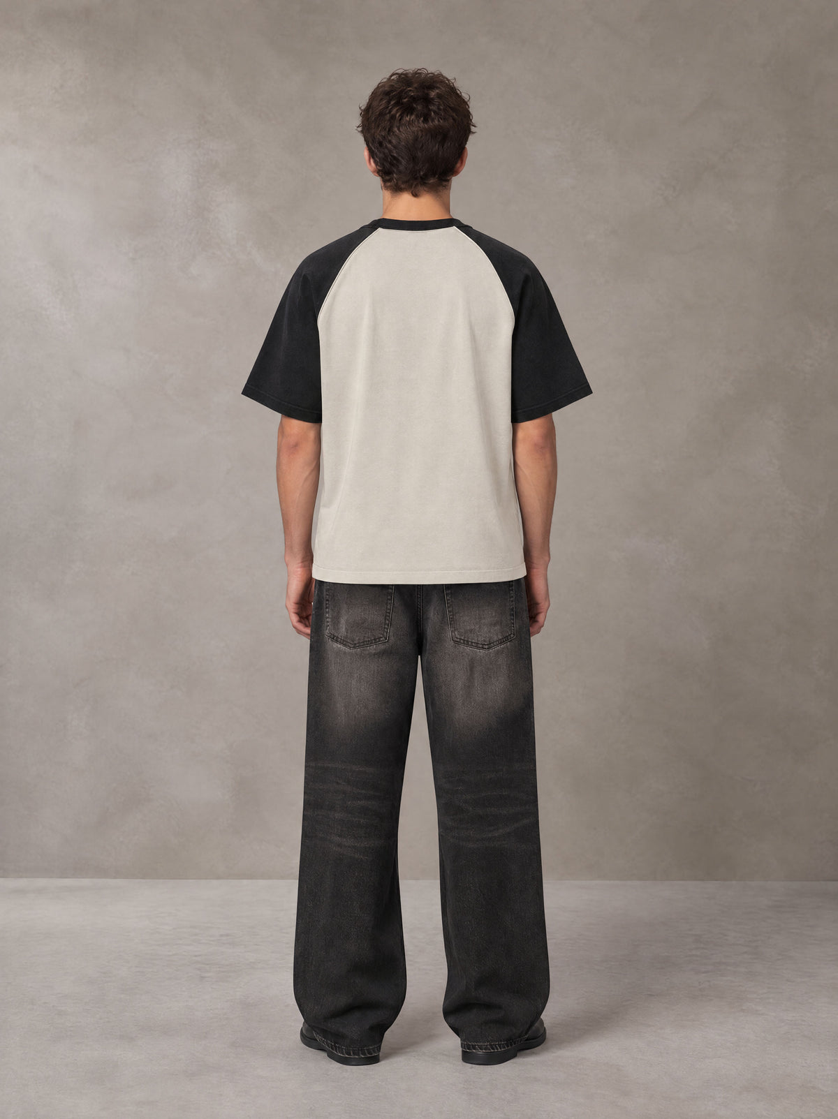 Model wearing the SM Royal Emblem T-shirt in Oatmeal Cookie, rear view.