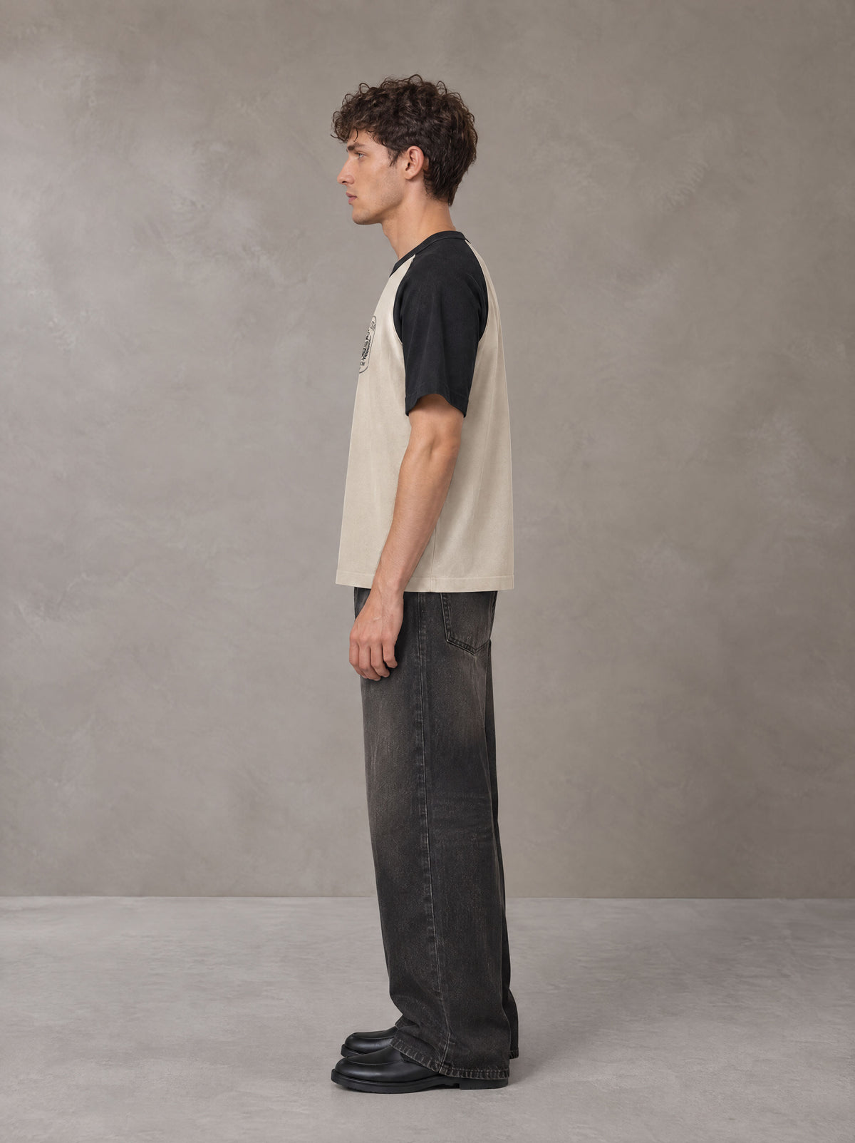 Model wearing the SM Royal Emblem T-shirt in Oatmeal Cookie, side profile.