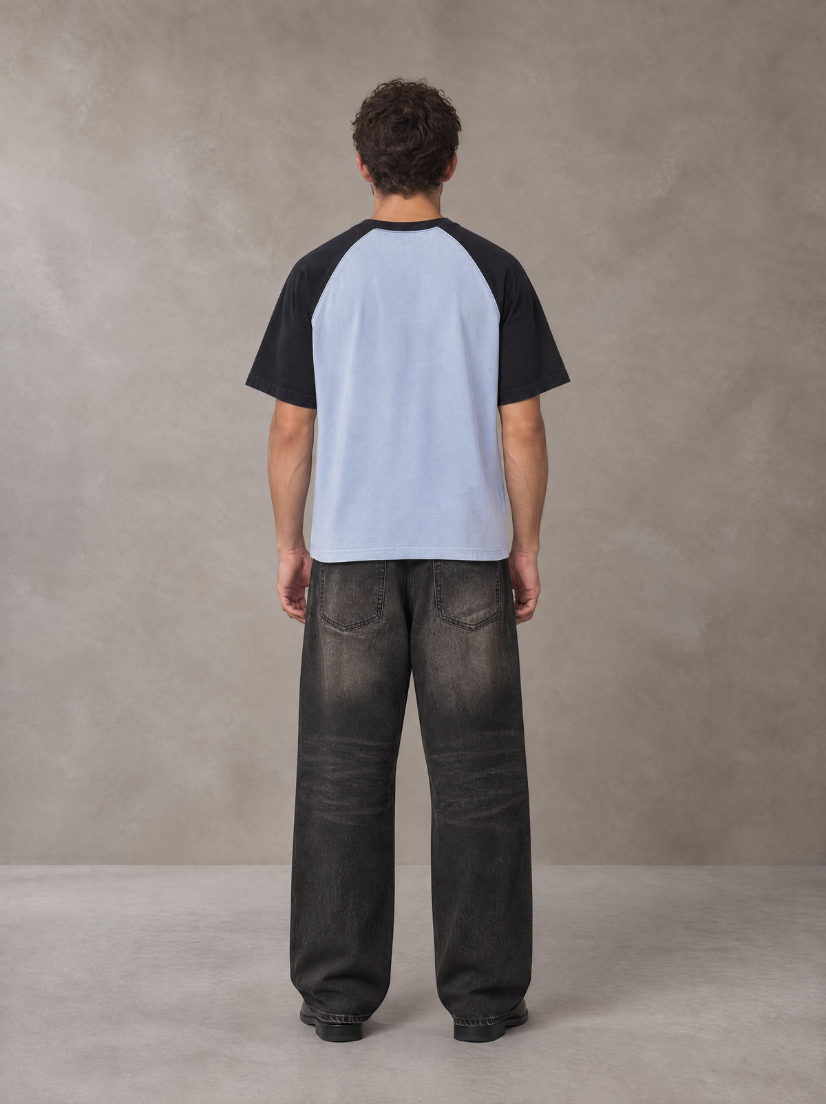 Model wearing the SM Royal Emblem T-shirt in Powder Blue, rear view.