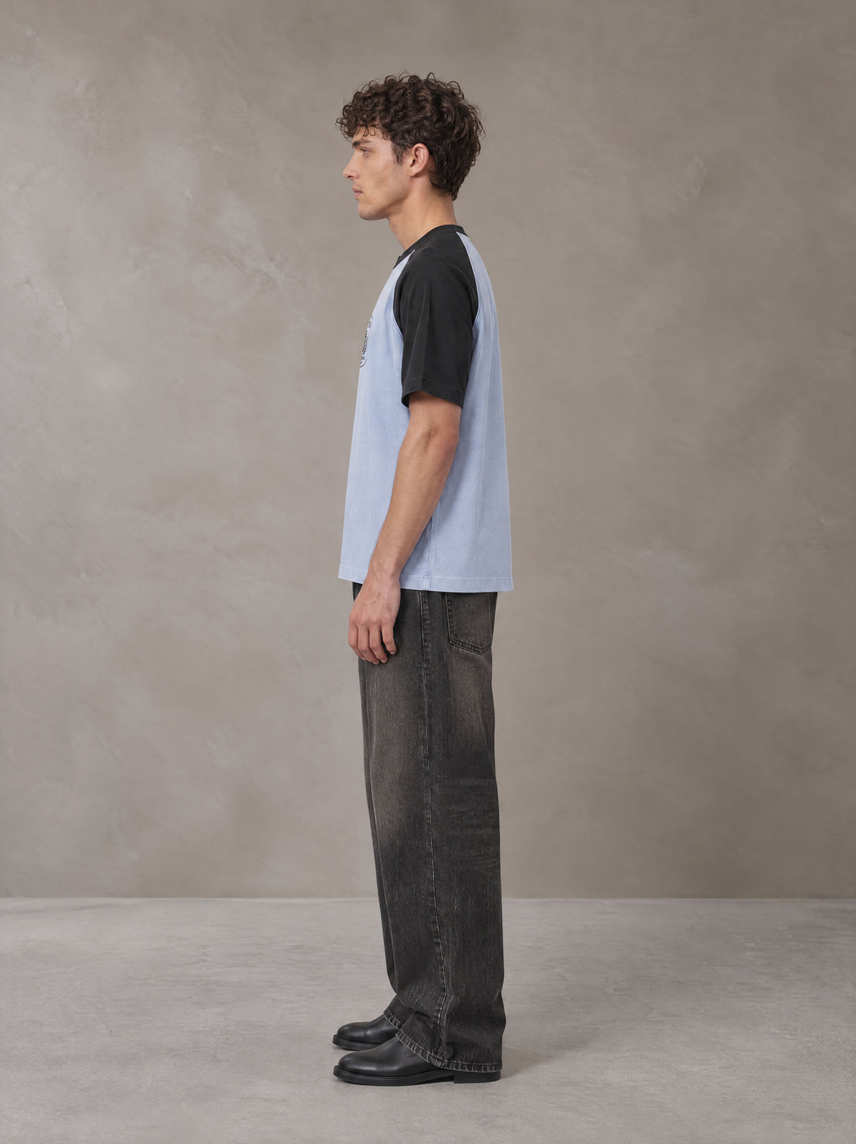 Model wearing the SM Royal Emblem T-shirt in Powder Blue, side profile.