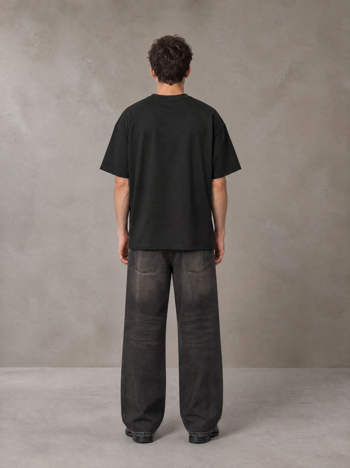 Model wearing the SM Celestial Charge T-shirt in Midnight Black, rear view.