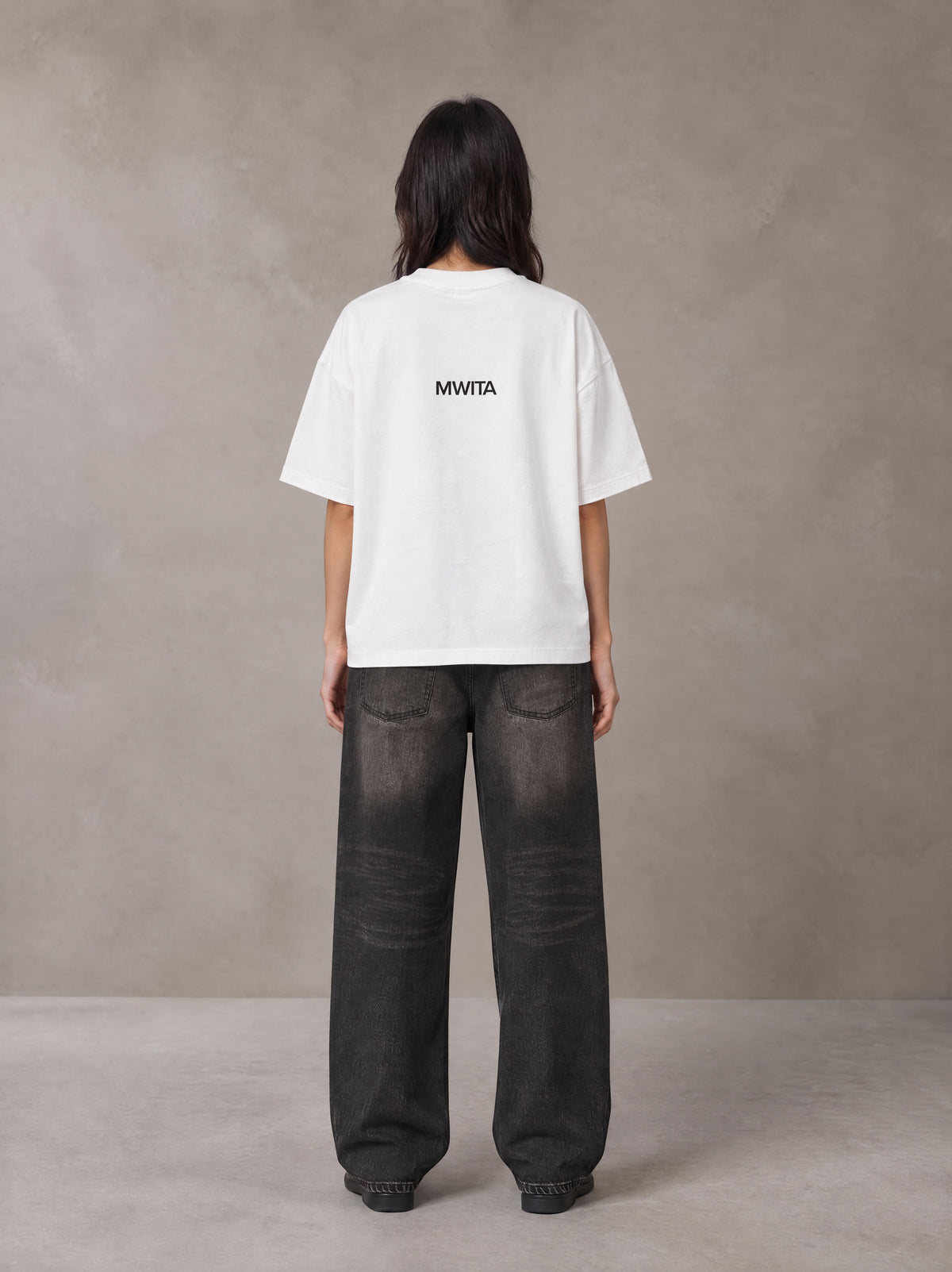 Model wearing the SM Fleur T-shirt in Lucent White, rear view.