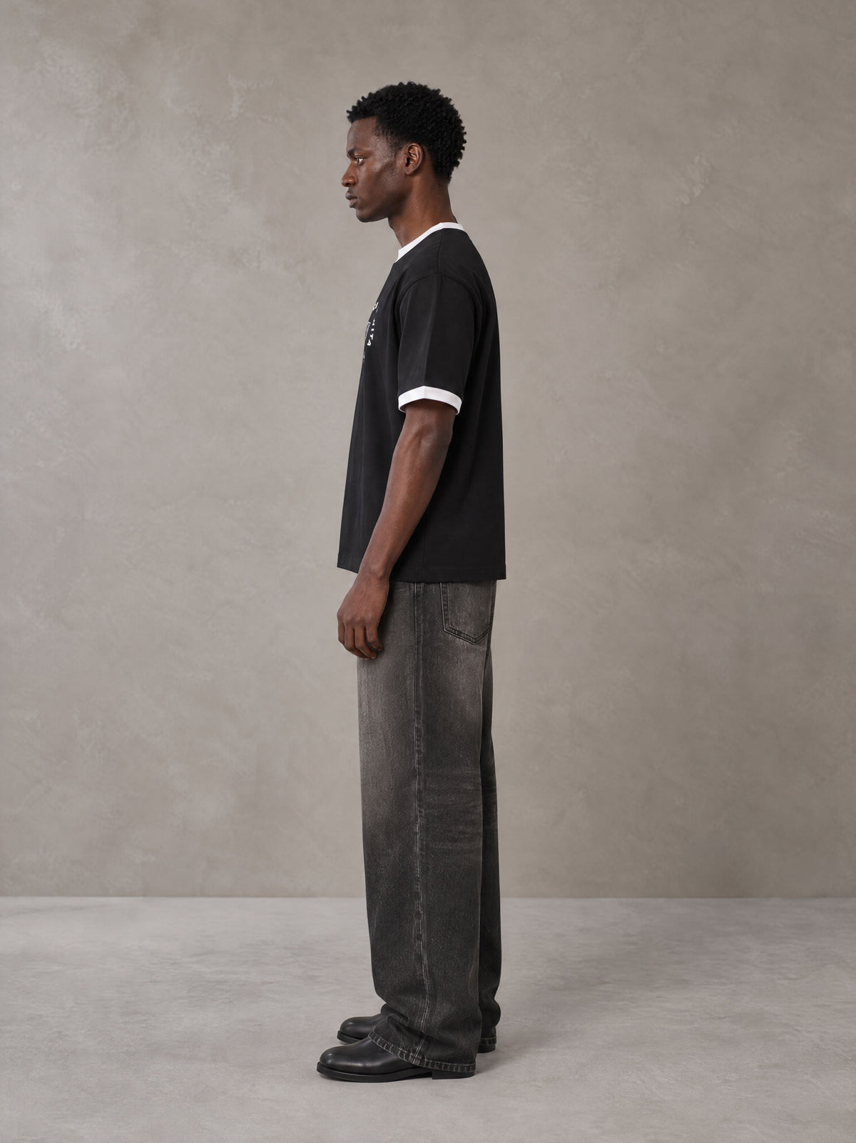 Model wearing the SM London T-shirt in Midnight Black, side profile.