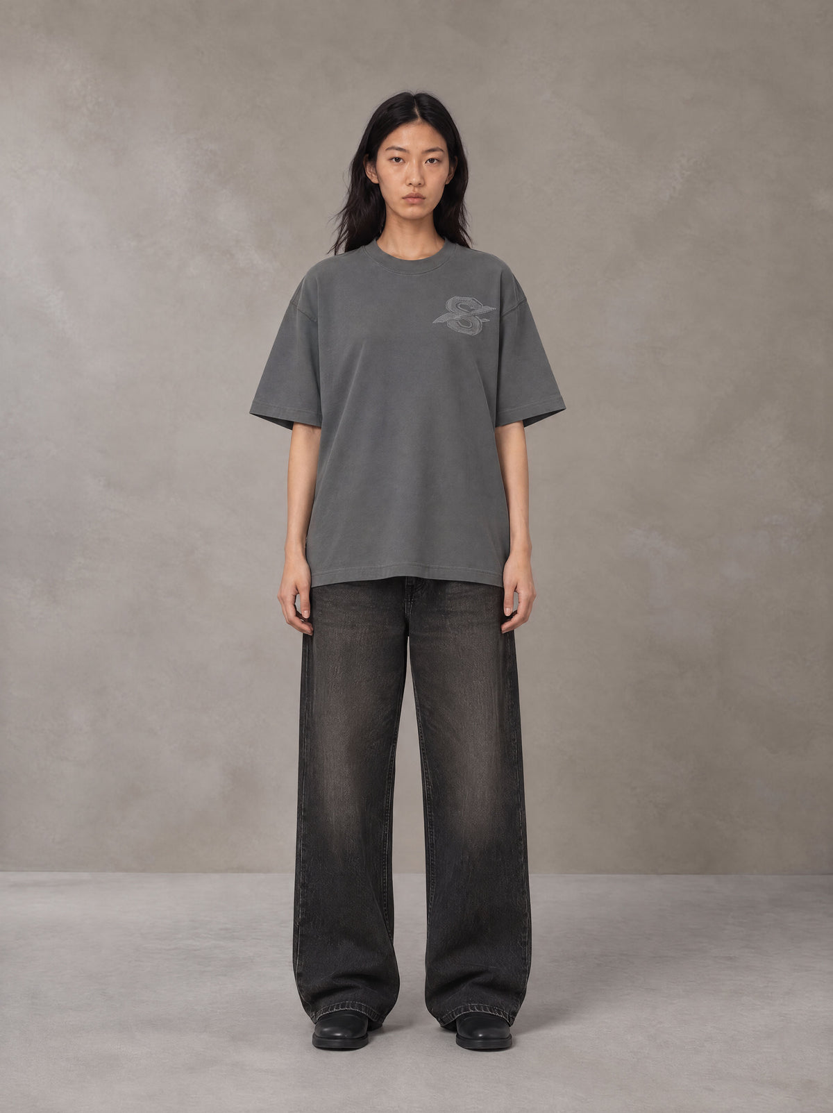 Model wearing the SM Carved Flight T-shirt in Deep Charcoal, front view.