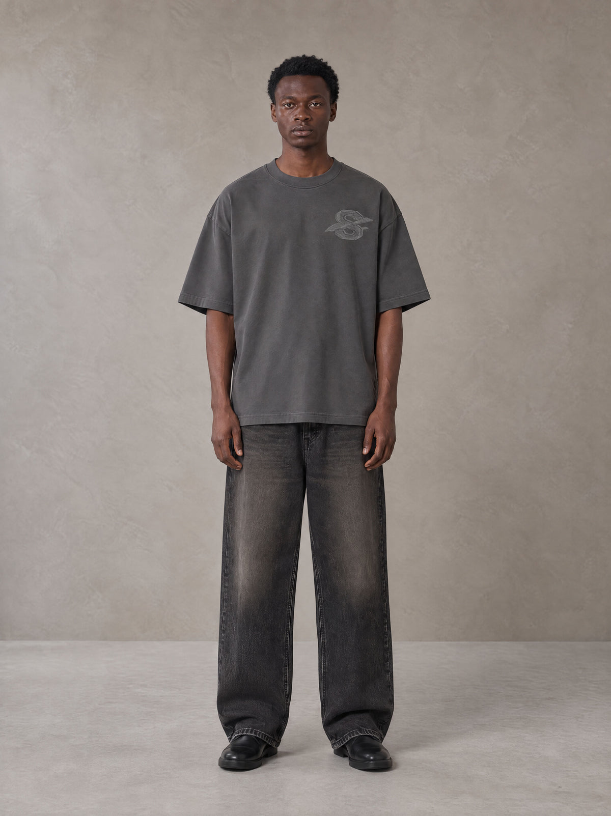 Model wearing the SM Carved Flight T-shirt in Deep Charcoal, front view.