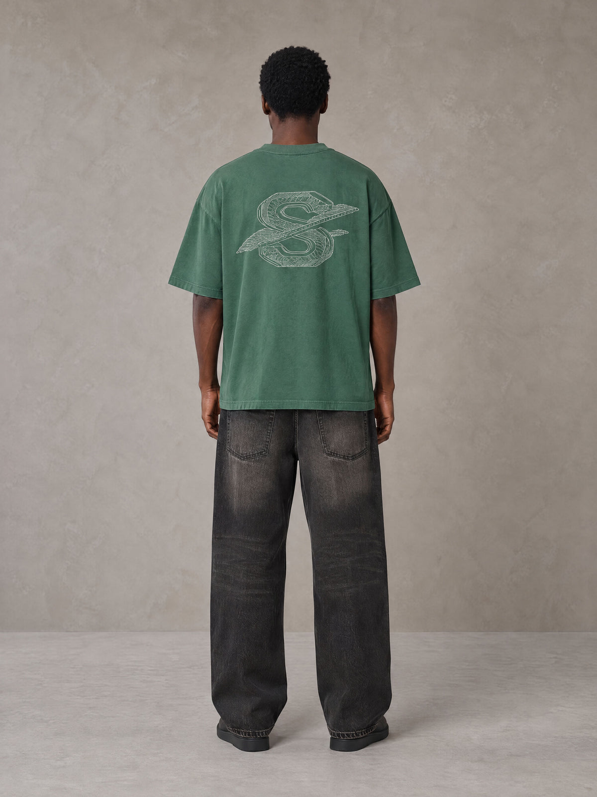 Model wearing the SM Carved Flight T-shirt in Forest Deep, rear view.