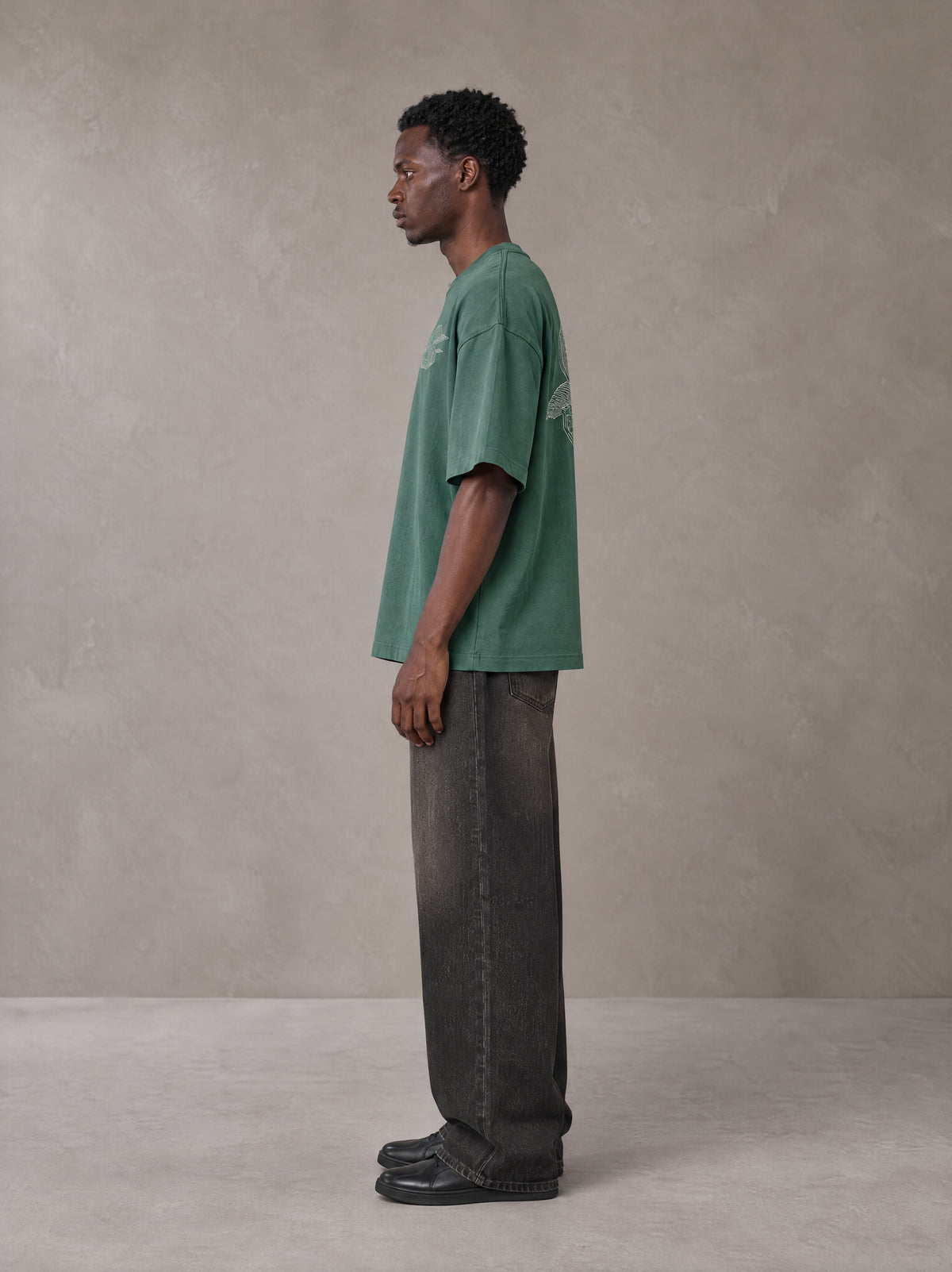 Model wearing the SM Carved Flight T-shirt in Forest Deep, side profile.