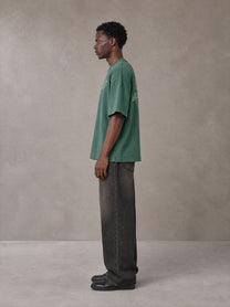 Model wearing the SM Carved Flight T-shirt in Forest Deep, side profile.