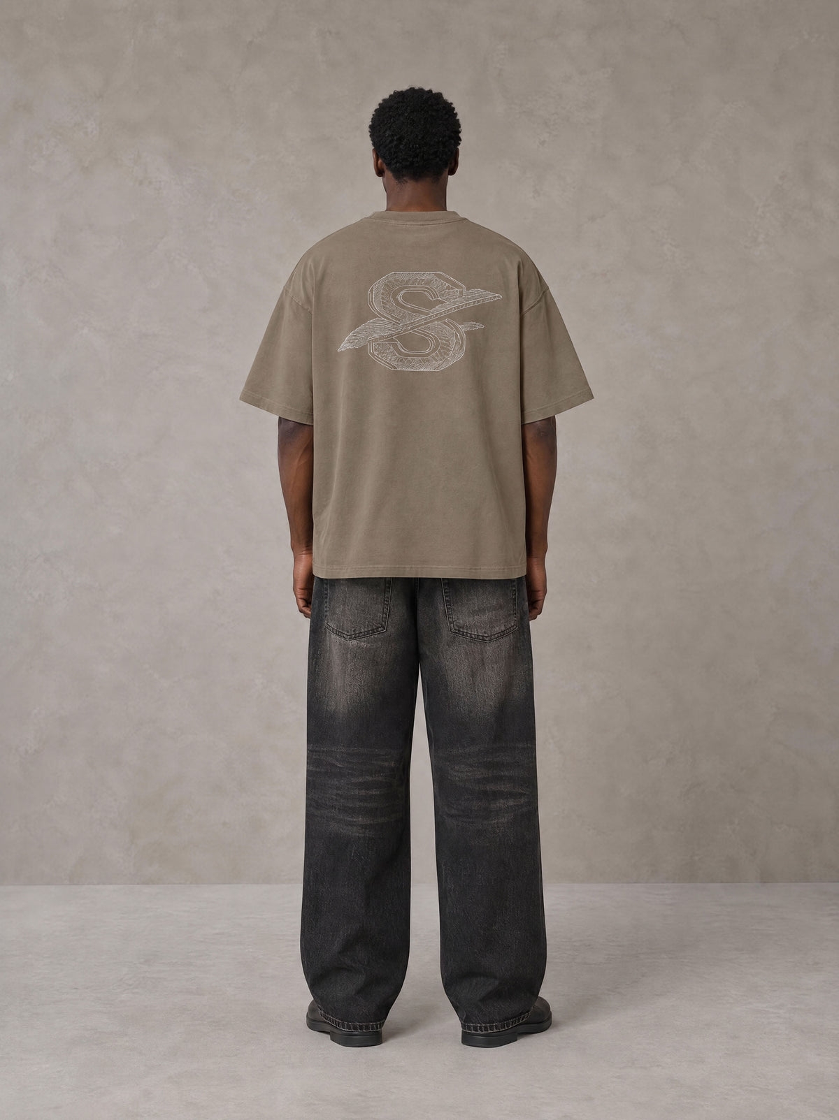Model wearing the SM Carved Flight T-shirt in Kabul Brown, rear view.