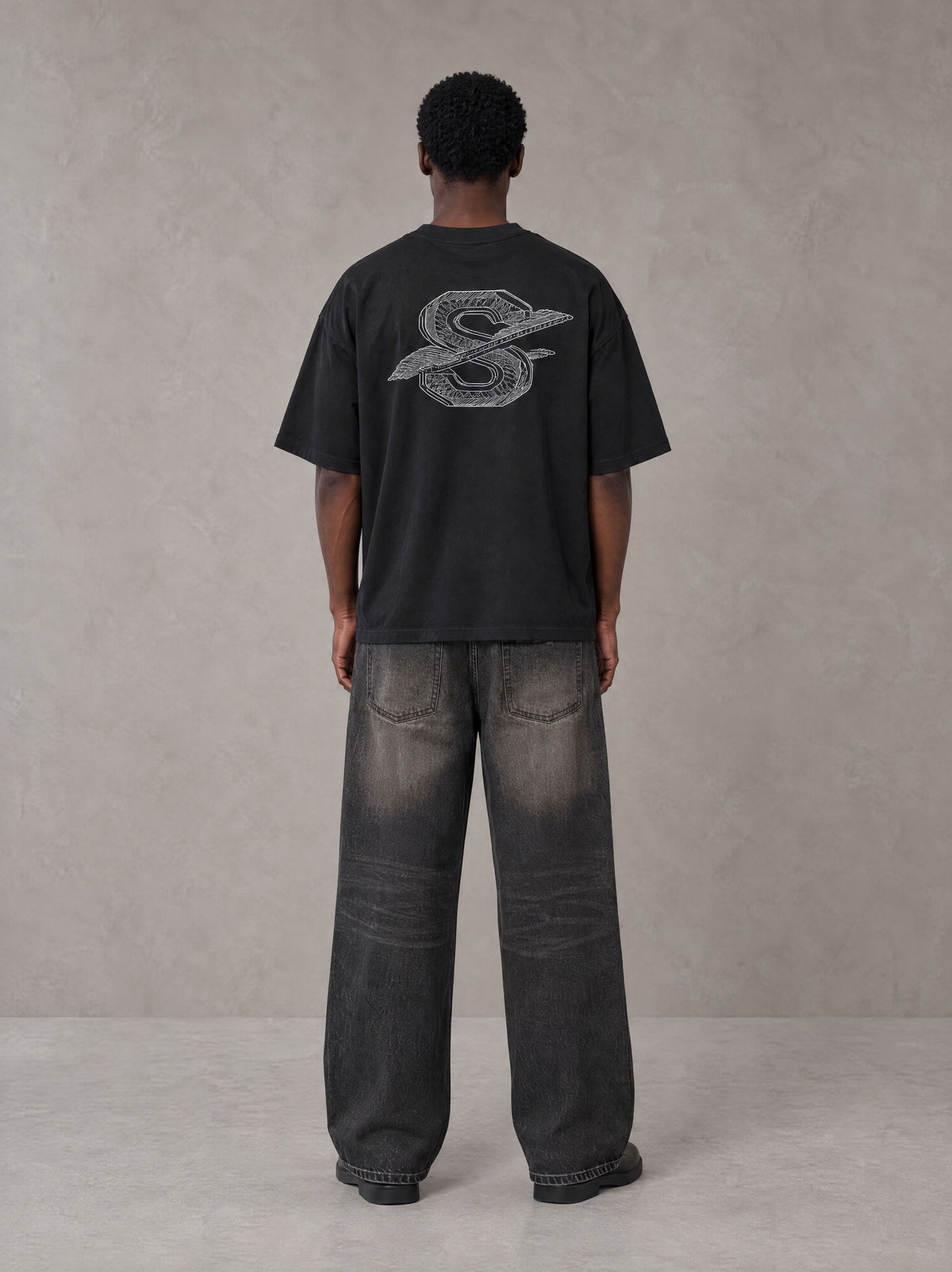 Model wearing the SM Carved Flight T-shirt in Midnight Black, rear view.