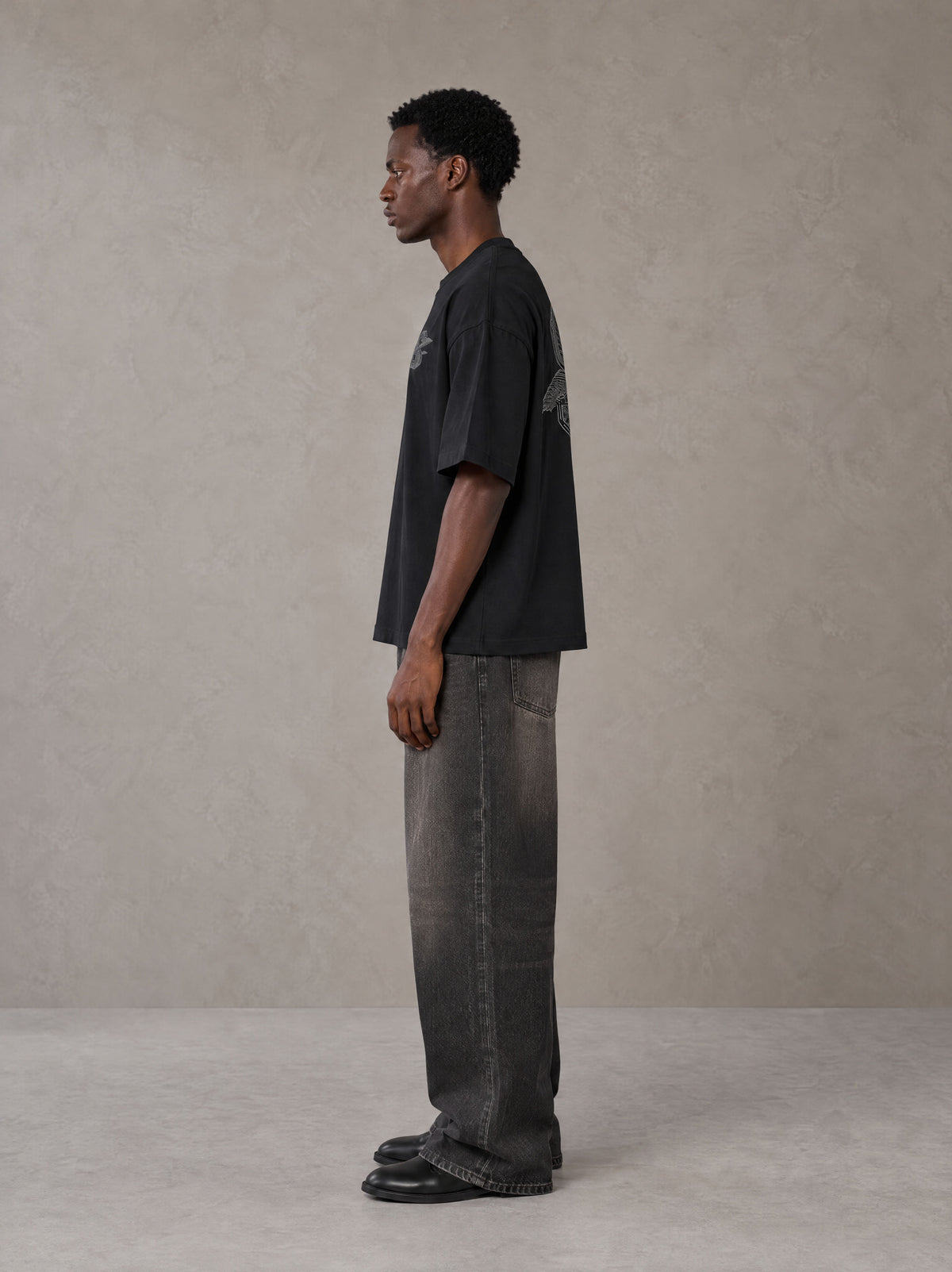 Model wearing the SM Carved Flight T-shirt in Midnight Black, side profile.