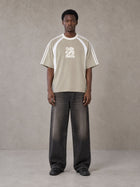 Model wearing the SM Cosmic Bloom T-shirt in Fine Sand, front view.