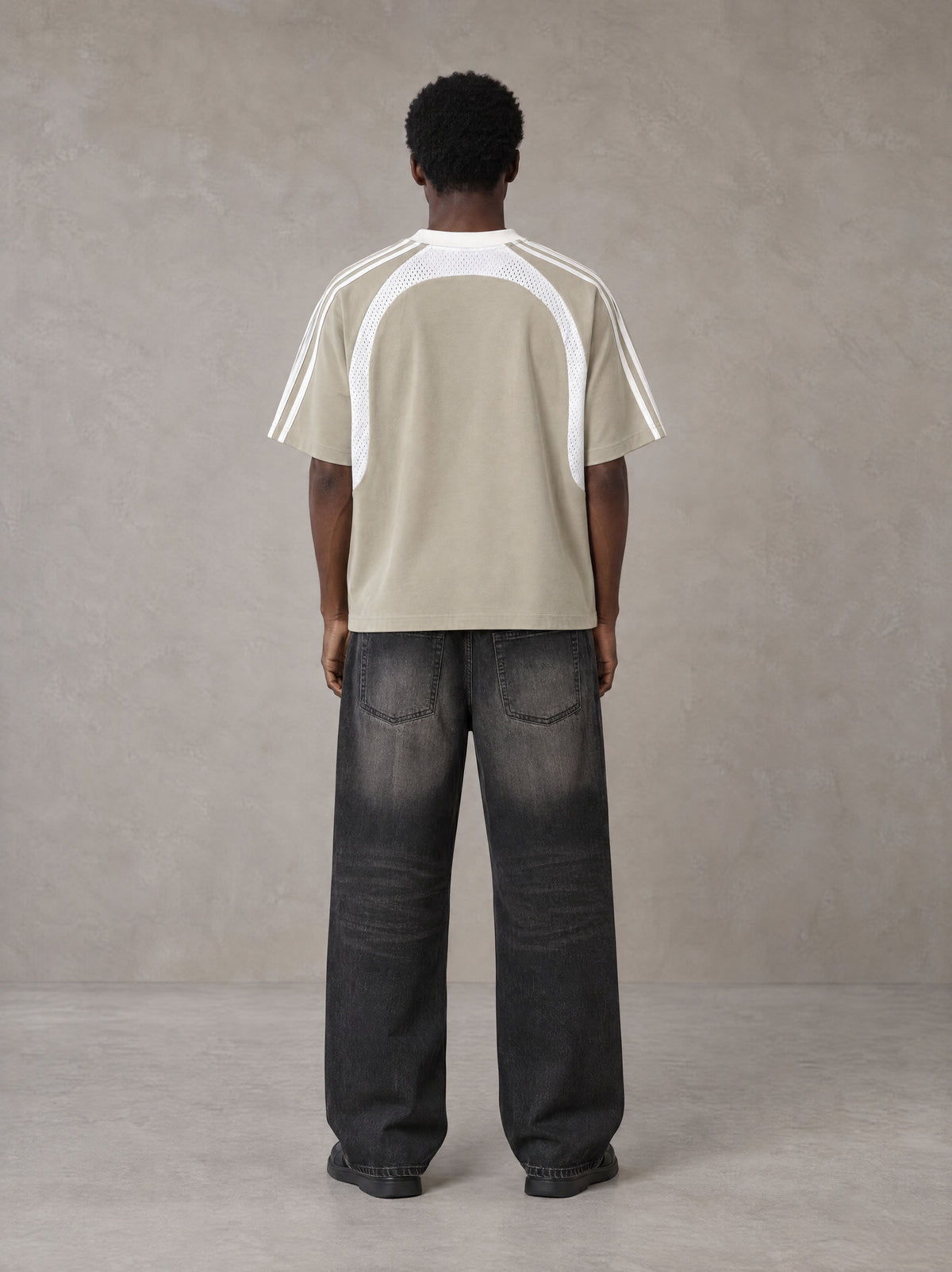 Model wearing the SM Cosmic Bloom T-shirt in Fine Sand, rear view.