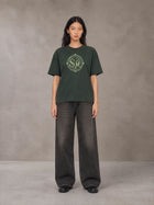 Model wearing the SM Emblem T-shirt in Dark Green, front view.