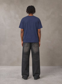 Model wearing the SM Emblem T-shirt in Oxford Navy, rear view.