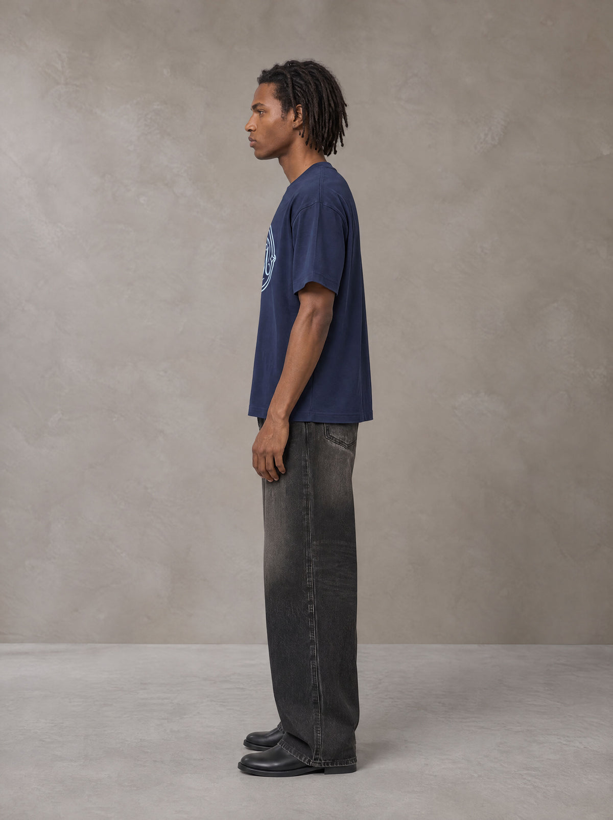 Model wearing the SM Emblem T-shirt in Oxford Navy, side profile.
