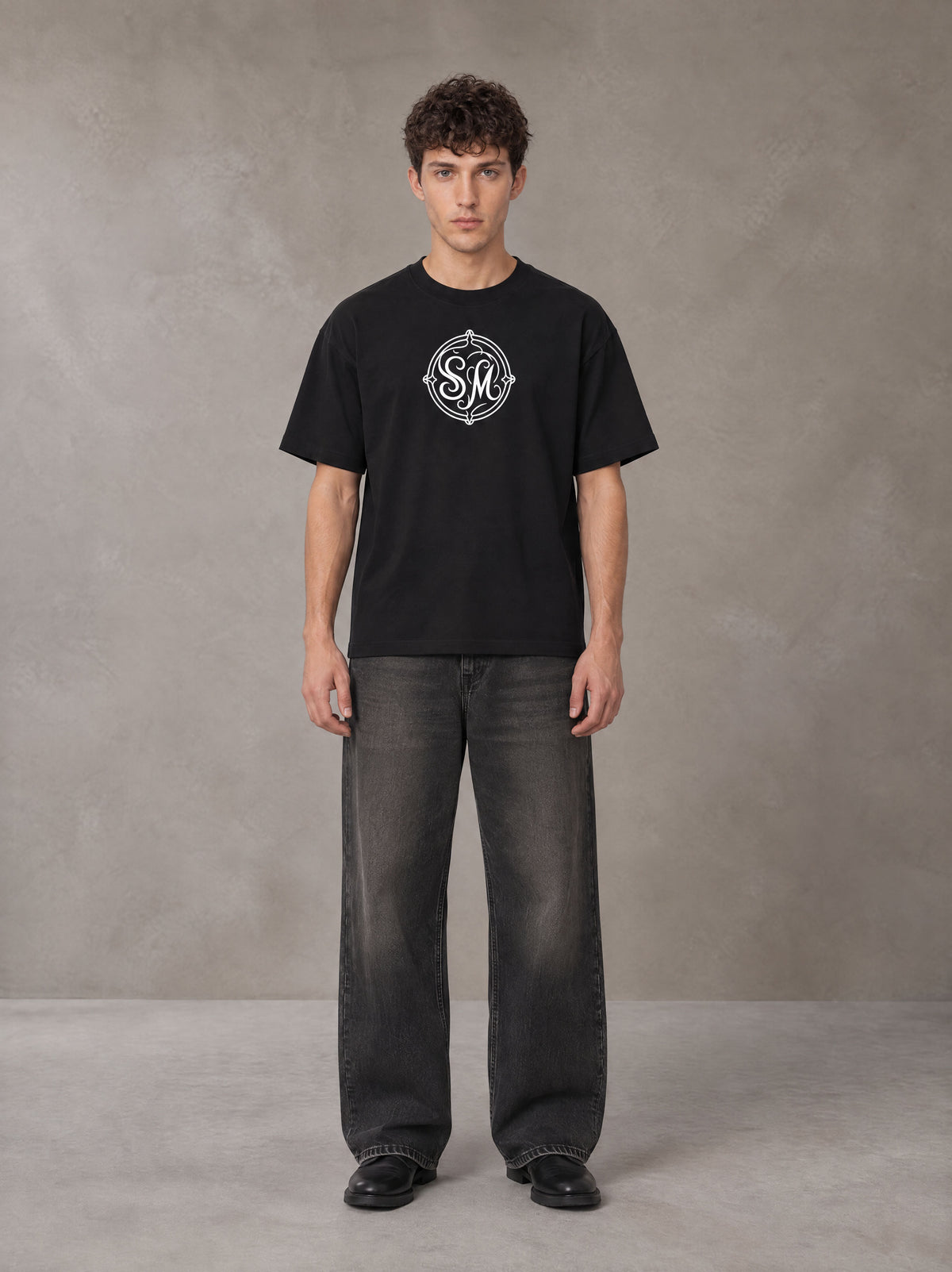 Model wearing the SM Emblem T-shirt in Midnight Black, front view.