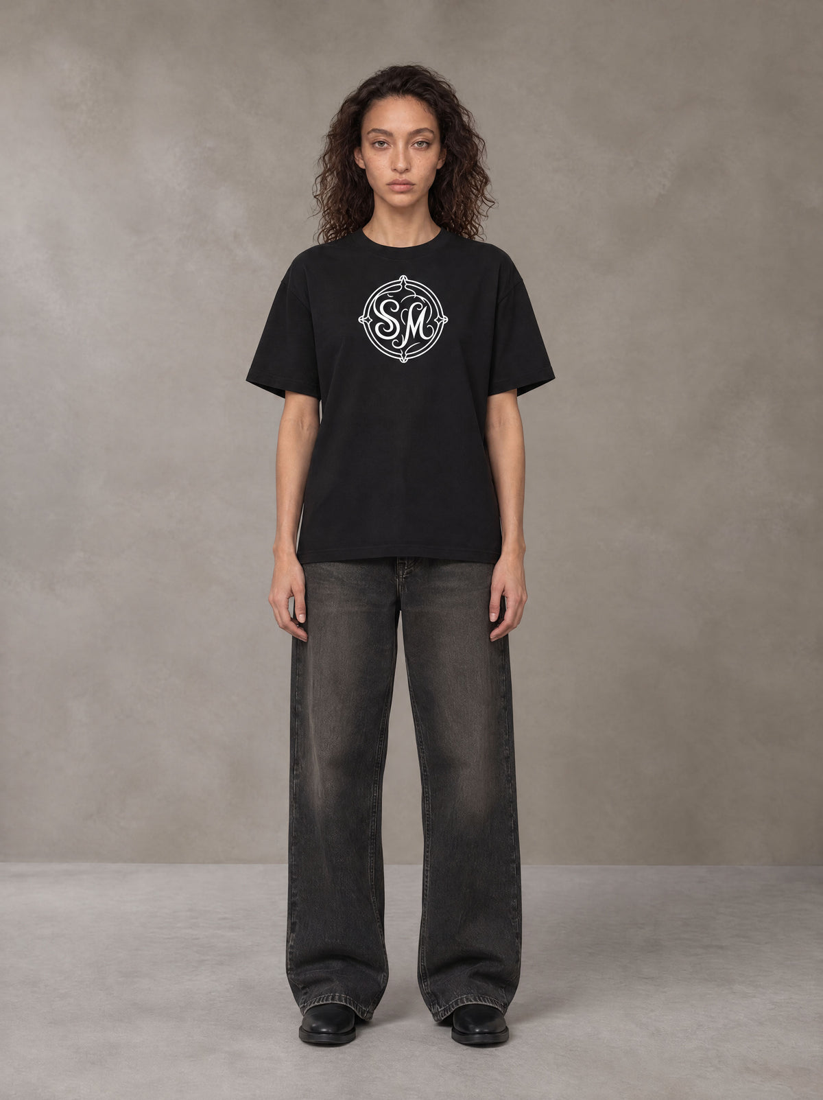 Model wearing the SM Emblem T-shirt in Midnight Black, front view.