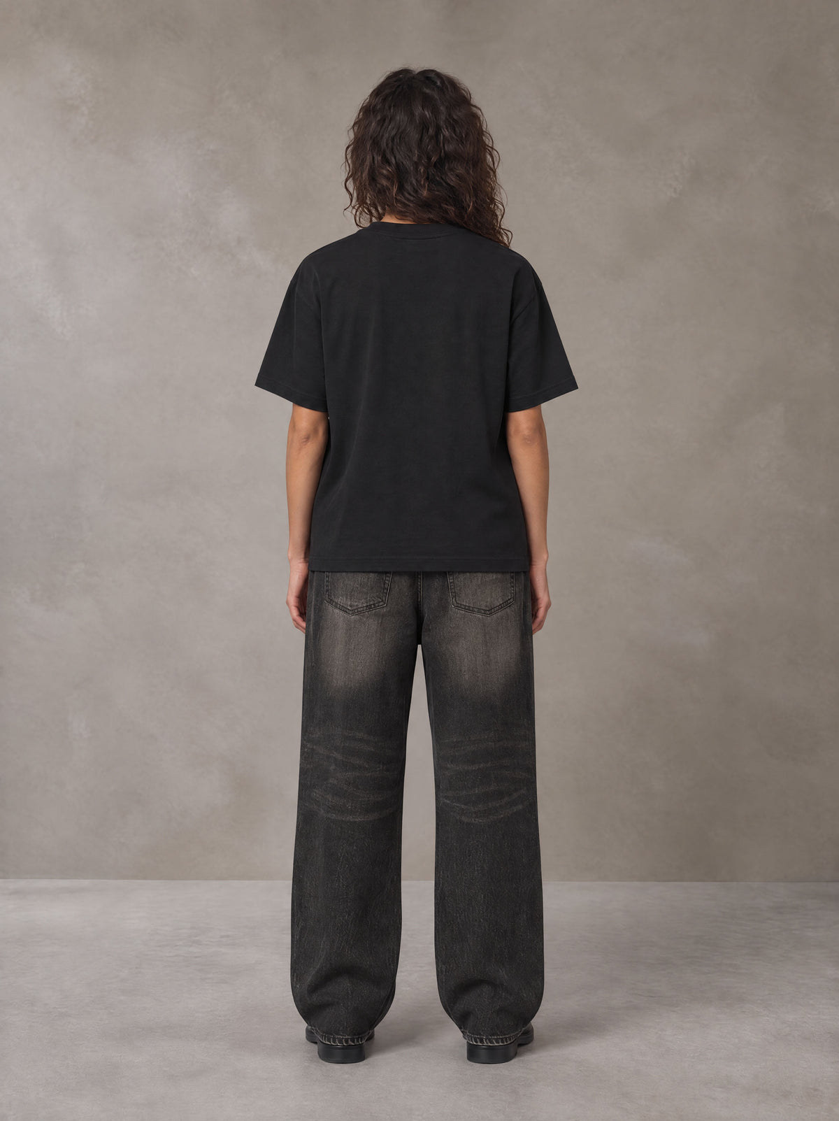 Model wearing the SM Emblem T-shirt in Midnight Black, rear view.