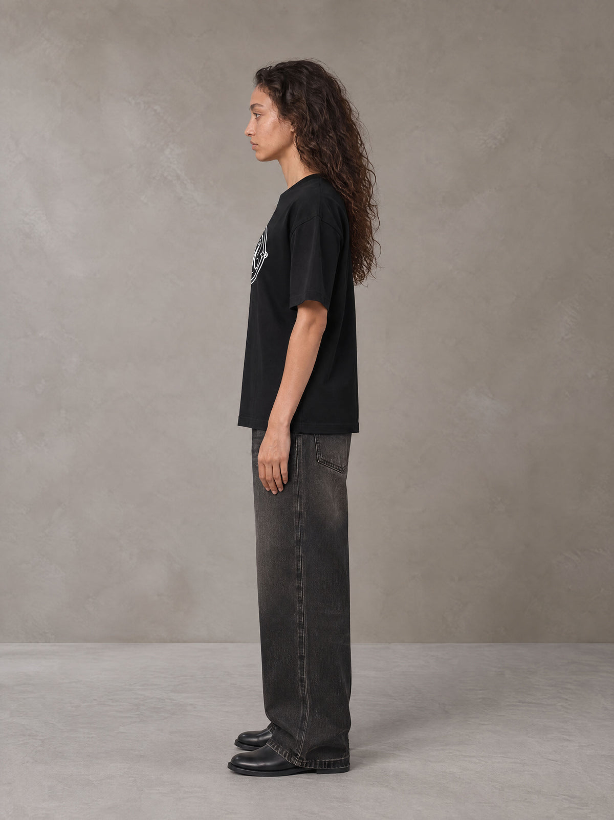 Model wearing the SM Emblem T-shirt in Midnight Black, side profile.