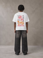 Model wearing the SM Floral Essence T-shirt in Lucent White, rear view.