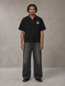Model wearing the SM Glyph Polo T-shirt in Midnight Black, front view.
