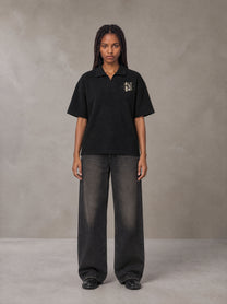 Model wearing the SM Glyph Polo T-shirt in Midnight Black, front view.