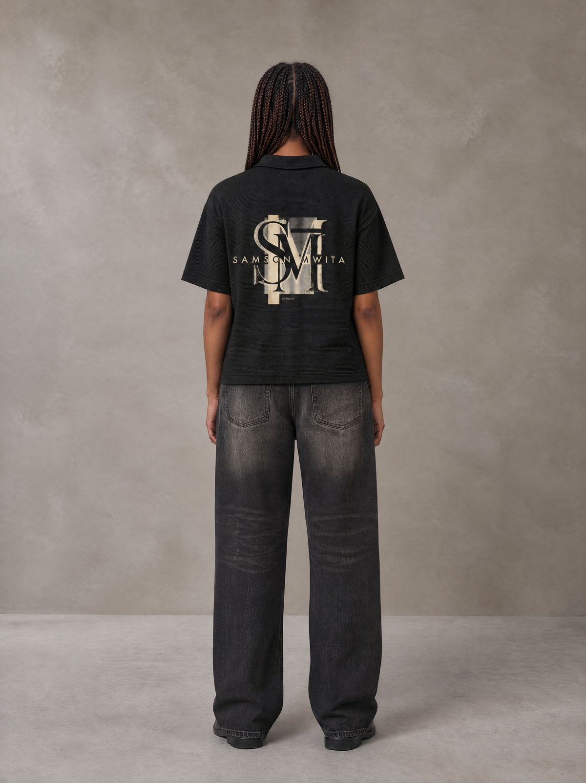 Model wearing the SM Glyph Polo T-shirt in Midnight Black, rear view.
