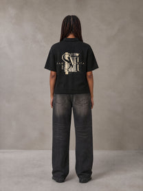 Model wearing the SM Glyph Polo T-shirt in Midnight Black, rear view.
