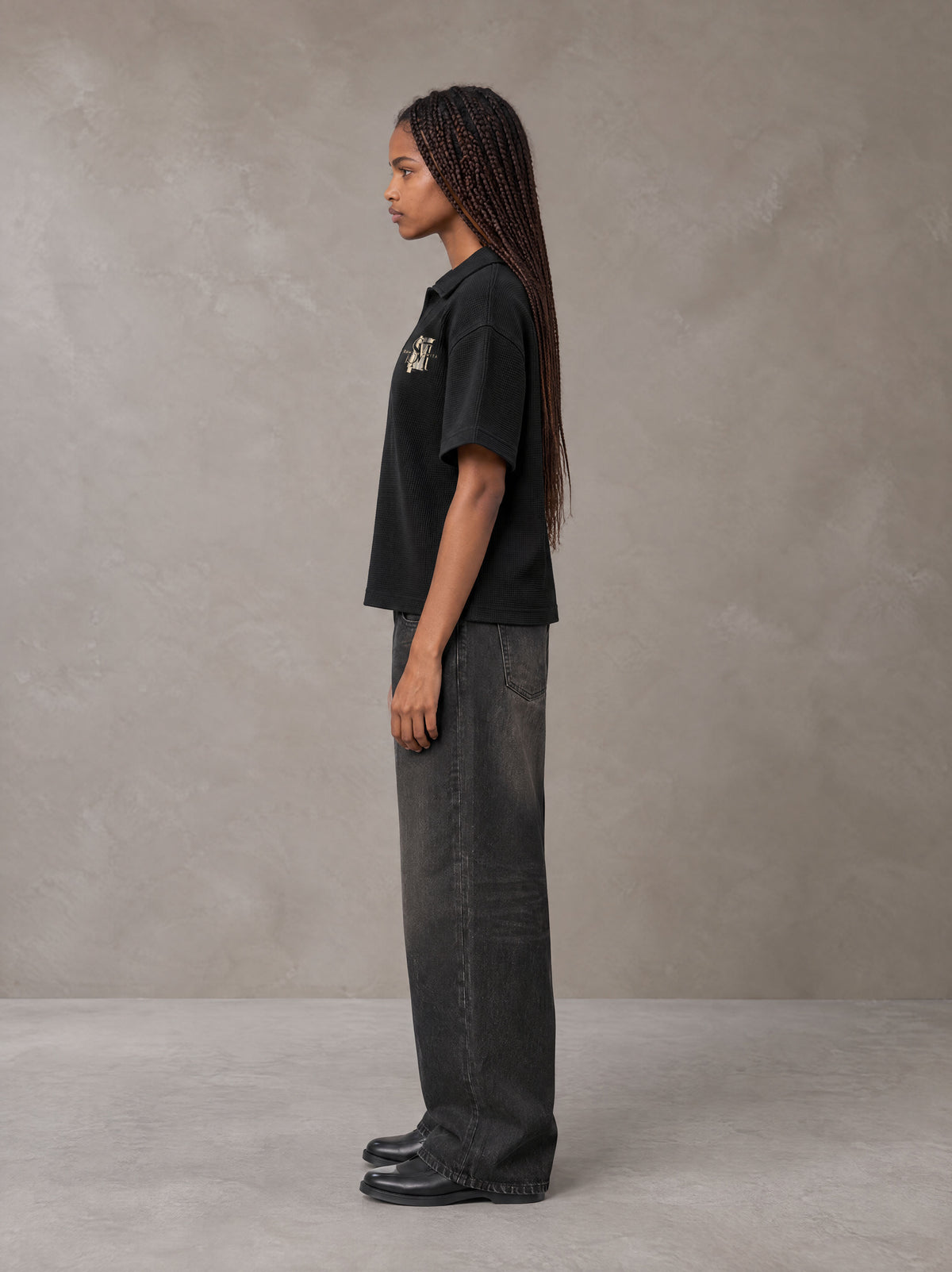 Model wearing the SM Glyph Polo T-shirt in Midnight Black, side profile.