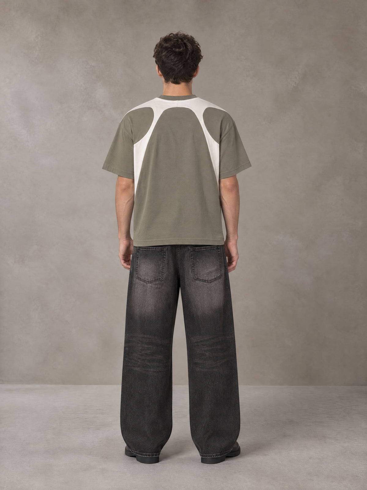 Model wearing the SM Graffiti Stack T-shirt in Coffee Grey, rear view.