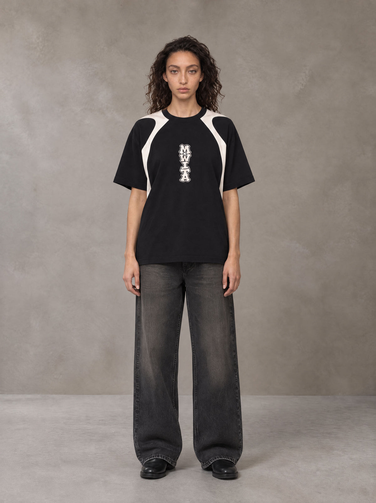 Model wearing the SM Graffiti Stack T-shirt in Midnight Black, front view.