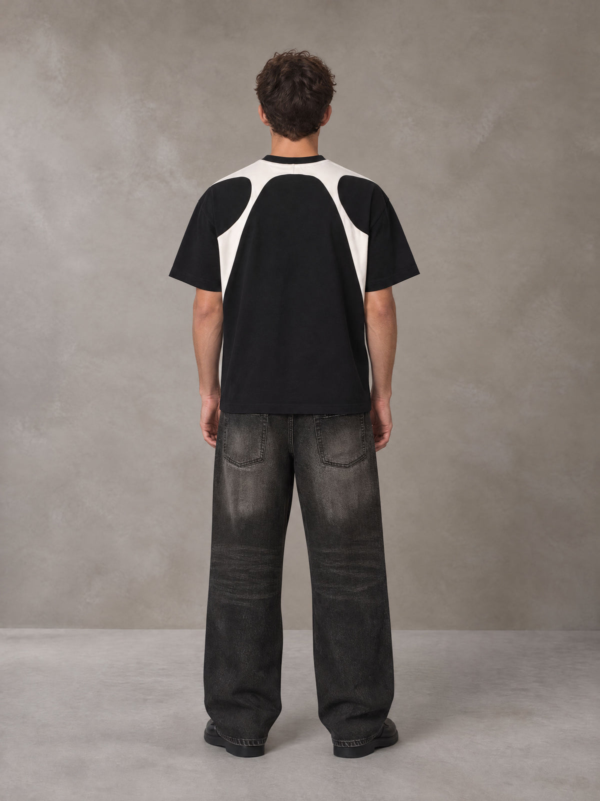 Model wearing the SM Graffiti Stack T-shirt in Midnight Black, rear view.