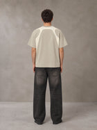 Model wearing the SM Graffiti Stack T-shirt in Oatmeal Cookie, rear view.