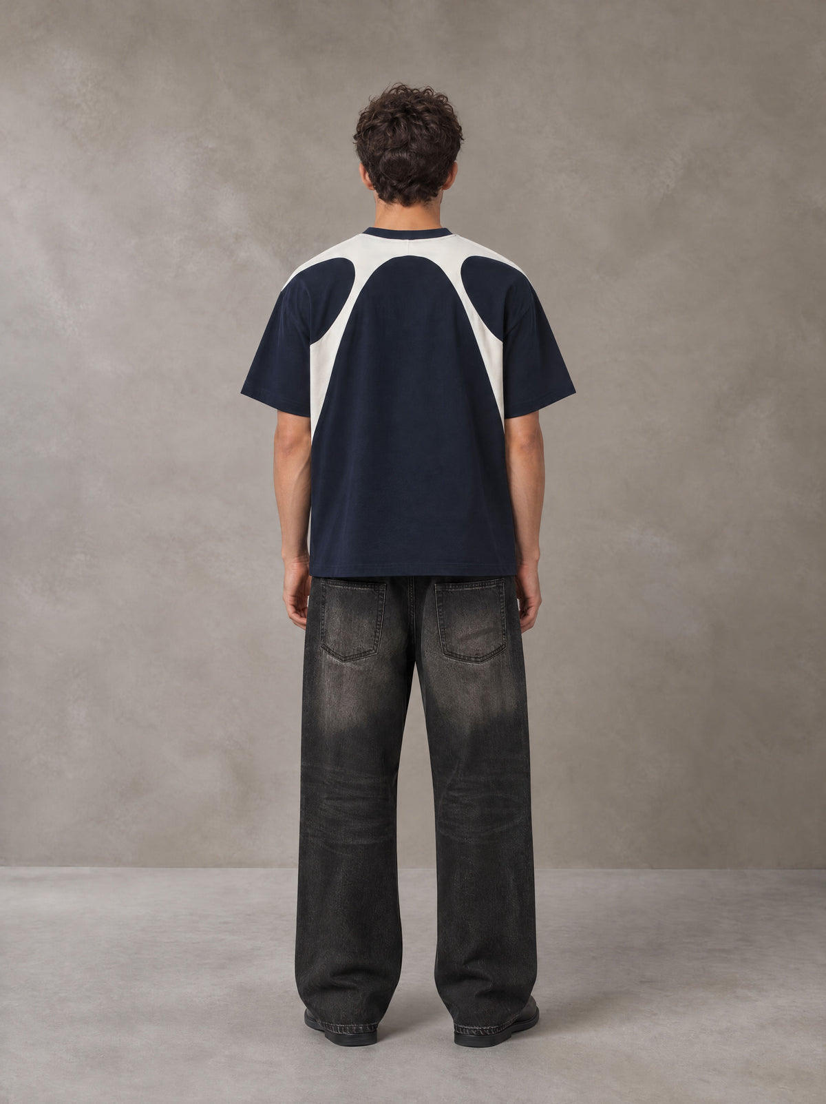 Model wearing the SM Graffiti Stack T-shirt in Oxford Navy, rear view.